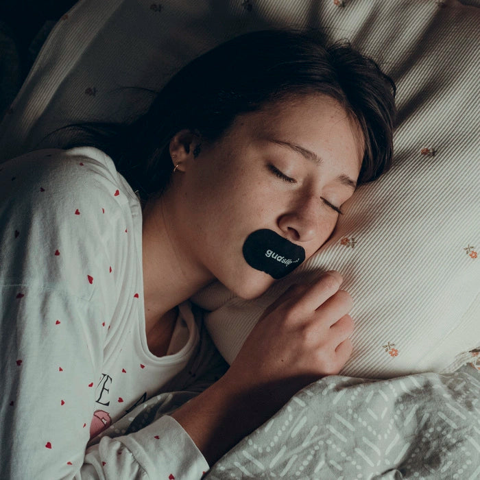 Žena během spánku používá pásky na ústa Gudslip, které zabraňují dýchání ústy a podporují přirozené nosní dýchání.